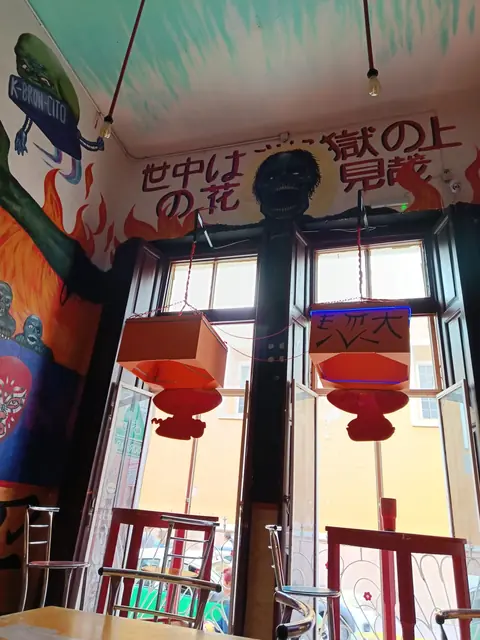 Ventanales hacia la calle con mural de flamas y letras japonesas arriba y faroles rojos colgando