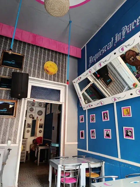 Rincón del salón azul con bocina, espejo decorado y mesas metálicas con sillas