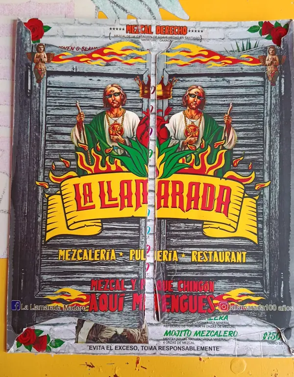 Portada de la carta de bebidas: puertas de cantina de madera, dos figuras de San Judas con lentes, llamas y el logo